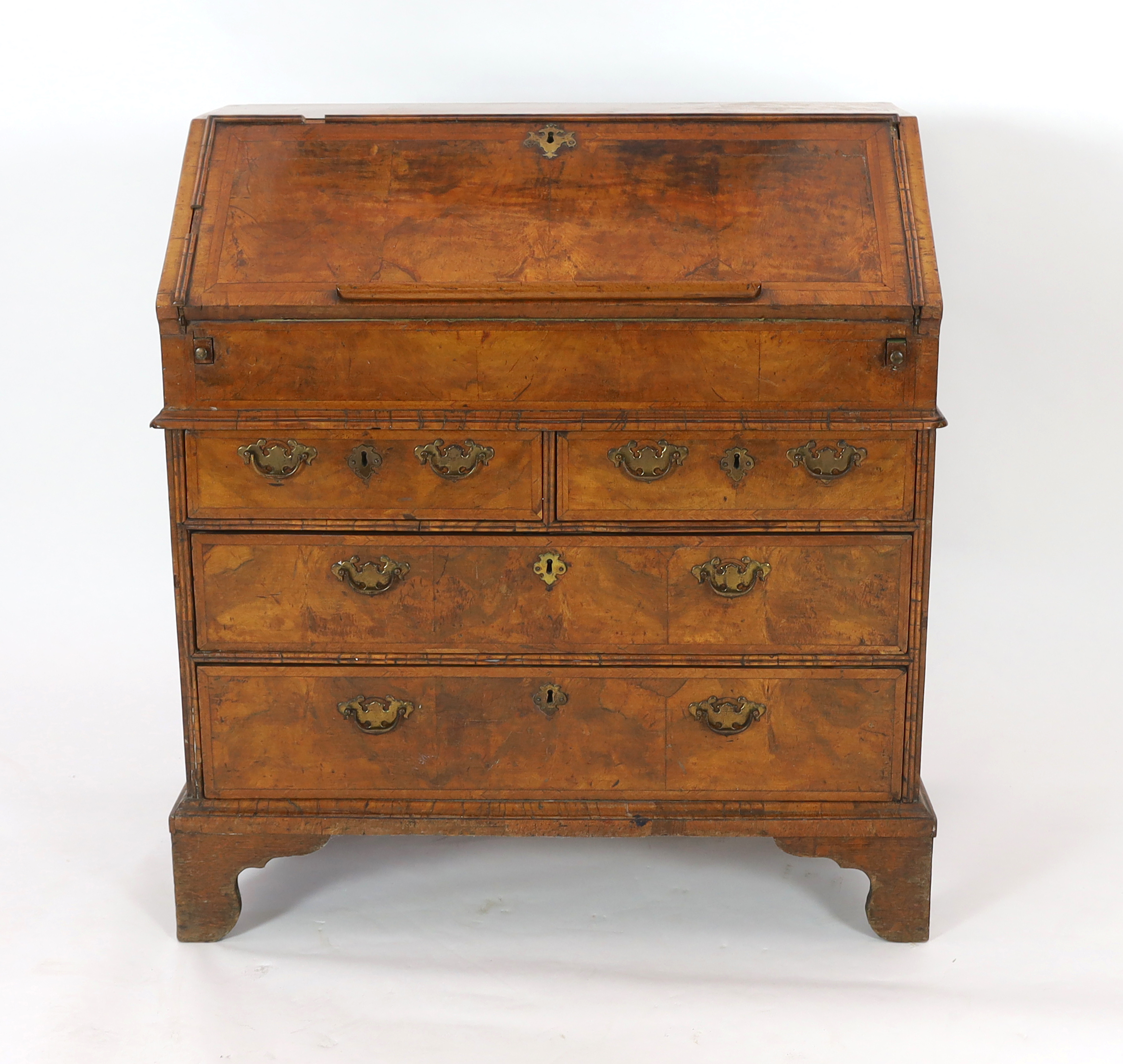 A George I figured walnut bureau, the fall enclosing an arrangement of pigeon-holes and short drawers over a well, above two short and two graduated long drawers, on bracket feet, 96cm wide, 52cm deep, 101cm high